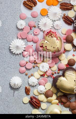 Assorted pink, orange, brown and green chocolate hearts with meringues, pecan nuts and chocolate drops Stock Photo