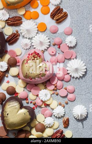 Assorted pink, orange, brown and green chocolate hearts with meringues, pecan nuts and chocolate drops Stock Photo