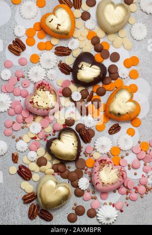 Assorted pink, orange, brown and green chocolate hearts with meringues, pecan nuts and chocolate drops Stock Photo