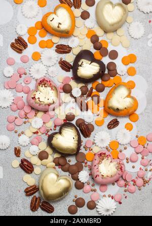 Assorted pink, orange, brown and green chocolate hearts with meringues, pecan nuts and chocolate drops Stock Photo