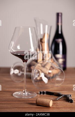 Glass of red wine, bottle, corkscrew, decanter with corks on wooden table, close-up, vertical, selective focus, side view, copy space Stock Photo