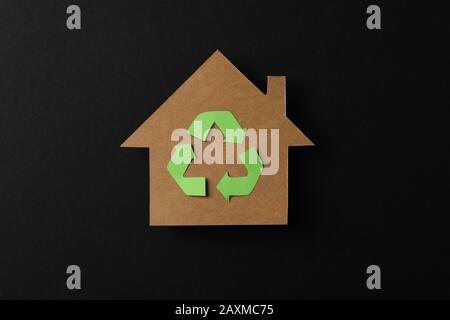 Cardboard house with recycling sign on black background, space for text Stock Photo