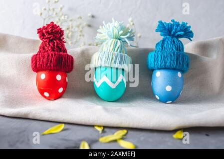 Bright colorful Easter eggs in a knitted winter hats on a gray background. Festive spring Easter card. Stock Photo