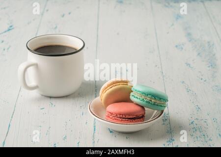 colorful french macaroons and a cup of coffee on a wooden table Stock Photo