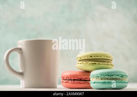 pile of colorful french macaroons and a cup of coffee on table over green with copy space Stock Photo