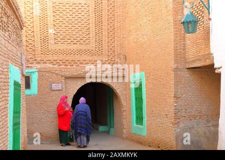 NEFTA, TUNISIA - DECEMBER 14, 2019: The historical brick decorated medina of Nefta, with women dressed with colorful clothes Stock Photo