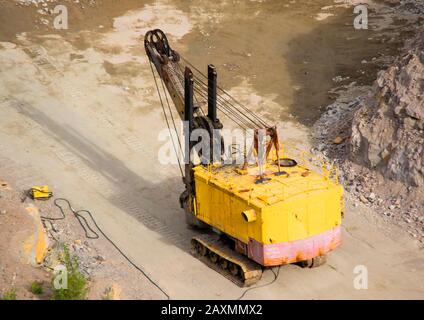 Old yellow excavator carver of iron stands on a platform in granite quarries Stock Photo