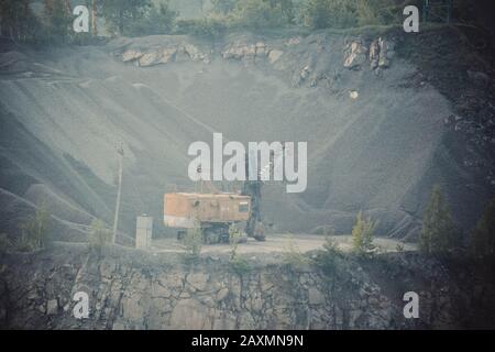 A large yellow excavator in a granite quarry, the filter Stock Photo