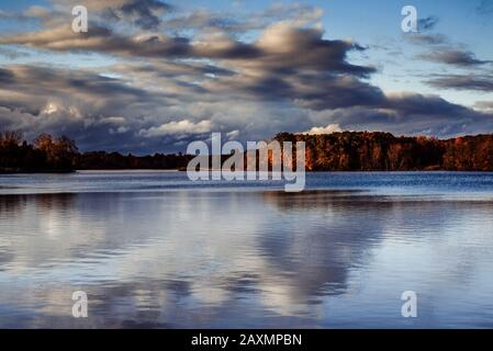 Reflection of Fall Colored Trees with a Cloudy Sky over Sand Lake Stock Photo