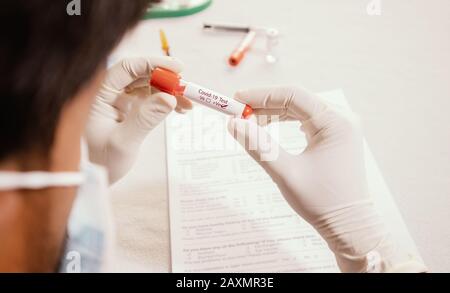 Doctor holding test tube with Positive Coronavirus or Covid-19 test blood sample - Concept of 2019-nCoV pandemic, Novel Chinese Coronavirus, Wuhan Stock Photo