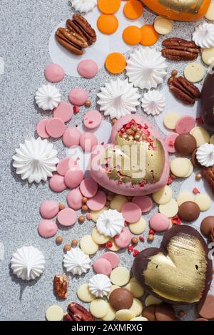 Assorted pink, orange, brown and green chocolate hearts with meringues, pecan nuts and chocolate drops Stock Photo