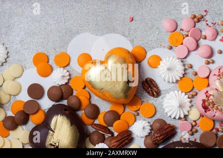 Assorted pink, orange, brown and green chocolate hearts with meringues, pecan nuts and chocolate drops Stock Photo