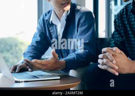 Closeup of two young businessmen using computer notebook at meeting. business partners to analyze financial data Stock Photo