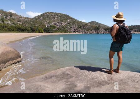 Backpacker with hat and swimsuit, on top of rock, admiring the bay Stock Photo