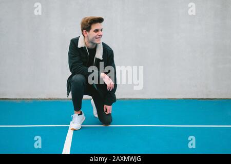 Man posing crouching on a paddle tennis court dressed casually Stock Photo