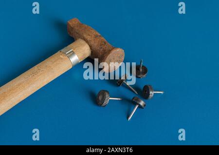 A small rusty hammer and five nails. Side view. Close-up. Selective focus. Stock Photo