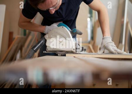 A man in safety glasses cuts metal with a special circular 