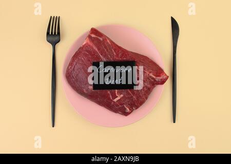A piece of raw meat lies on a plate. Veal tenderloin. Predatory diet label. Zero carbohydrate diet concept. Ketogenic diet, Stock Photo