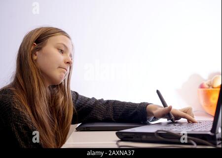 girl at home learns to draw on the laptop using a tablet and pen Stock Photo
