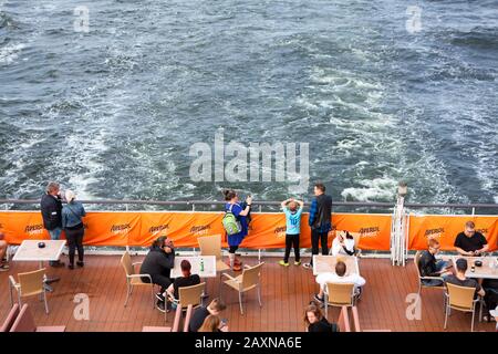 BALTIC SEA, SWEDEN - CIRCA JUN, 2018: Passengers stand on stern of cruise ferry. Tables, chairs, couches are in beck bar for people pleasure. It is sh Stock Photo