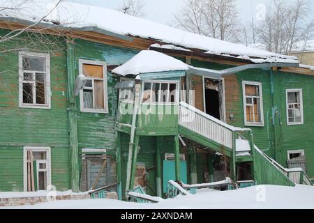 Ruined old two-story apartment building. Green wooden house with stairs leading to the second floor street. Stock photo with empty space for text. Stock Photo