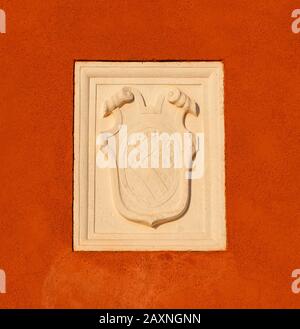 Old heraldic emblem with a damaged relief on a Venice red plaster wall Stock Photo