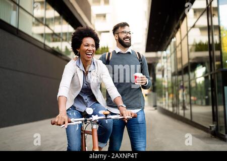 Happy business couple riding bike through city and having fun Stock Photo