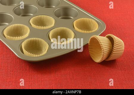 Parchment paper muffin cups and nonstick muffin pan on red background Stock Photo