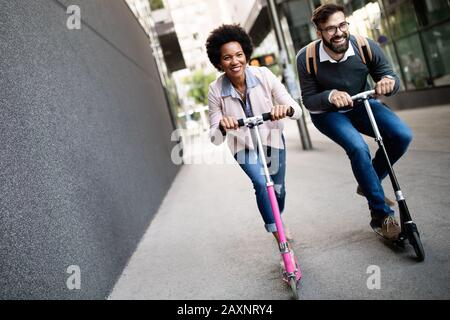 Happy young couple enjoying together while riding electric scooters on city street Stock Photo