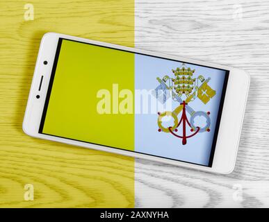 Flag of the Vatican City composed by placing a smartphone displaying its symbol on a colored wooden background