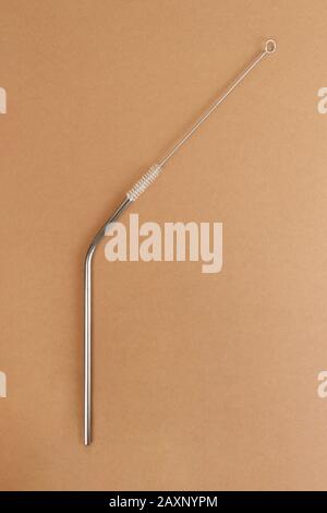Eco-friendly reusable metal drinking straw and steel brush for cleaning on a beige background. Stainless reusable bar equipment for drinking alcoholic Stock Photo