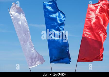 Three colorful flags on flagpoles against blue sky with perspective, corporate flag ,symbol, copy space. Stock Photo