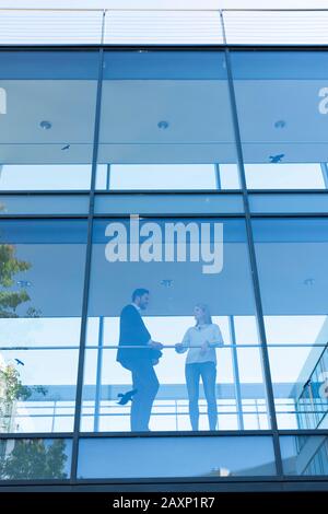 Young businessman and young businesswoman in modern office building behind glass front Stock Photo