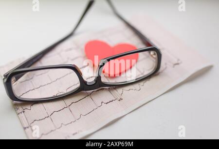 Cardiogram chart with glasses and red heart on table closeup. Cardiovascular Disease Prevention Stock Photo