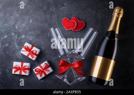 Valentine's day greeting card template from champagne bottle, two luxury glasses with a red satin ribbon bow, two handmade hearts and three gift boxes Stock Photo