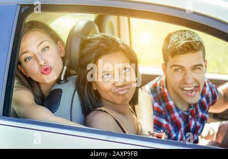 Happy students friends making funny faces in camera inside car - Young people having fun traveling in summer trip around europe - Vacation and friends Stock Photo