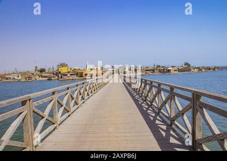 Long wooden bridge leading over a sea lagoon. It leads to Fadiouth Island in Senegal, Africa. It is a beautiful natural background. Stock Photo