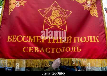 Sevastopol, 9th of May, 2019 A man holds banner with inscription in Russian 'The Immortal Regiment Sevastopol' during the parade on central street in Sevastopol city, Crimea Stock Photo