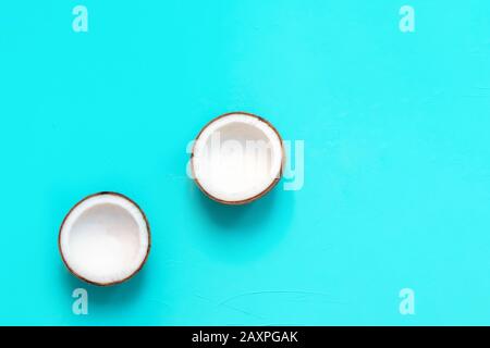 Fresh coconut halves on light blue background. Top view with copy space Stock Photo