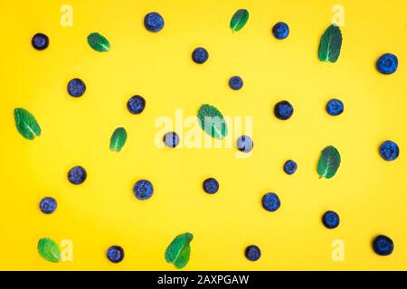 Fresh ripe blueberry with mint leaves on yellow background. Blueberry pattern Stock Photo