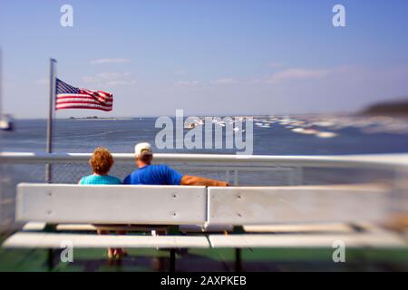 A senior couple relaxing on a bench on board a ferry in Long Island sound, Connecticut USA Stock Photo