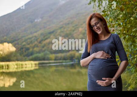 Pregnant wife on posing on the lake Stock Photo