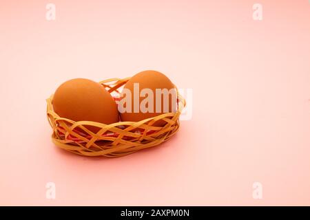 Wicker basket with Easter eggs on pink background Stock Photo