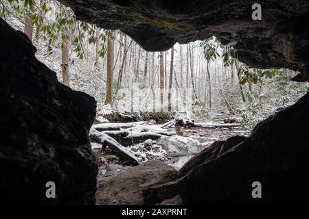 Snow-covered forest scene framed by cave walls in Pisgah National Forest, near Brevard, North Carolina, USA Stock Photo