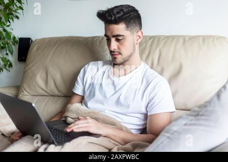 Young male man relaxing on sofa while using laptop Stock Photo