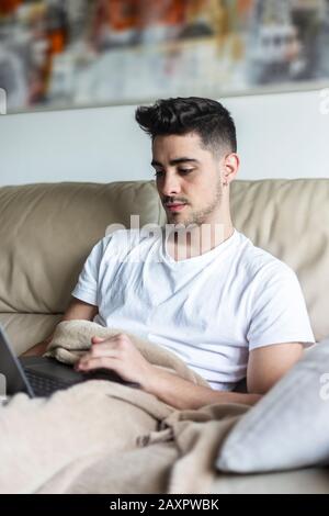 Young male man relaxing on sofa while using laptop Stock Photo