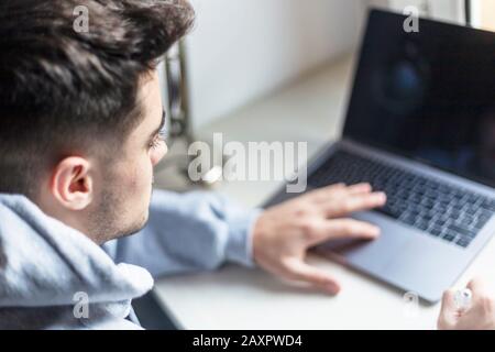 Rear view of a young man working with laptop on desktop Stock Photo