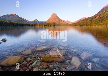View of mountains reflecting in Two Medicine Lake in Glacier Park Stock Photo