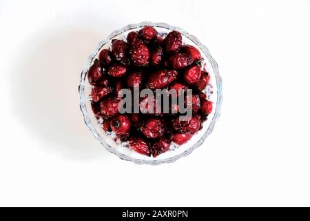 Red dried rose hips (berry, fruit) are in glass jar on red background Stock Photo