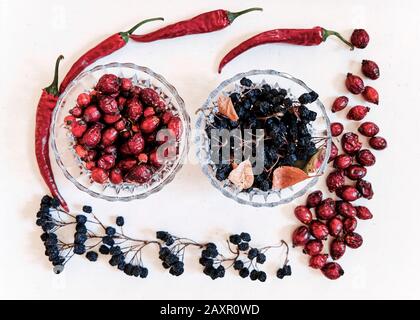Dried red chili peppers, rose hips, black aronia on white background Stock Photo